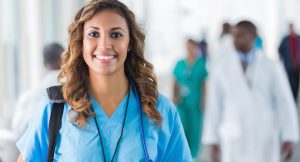 Friendly young hospital nurse walking through busy hallway