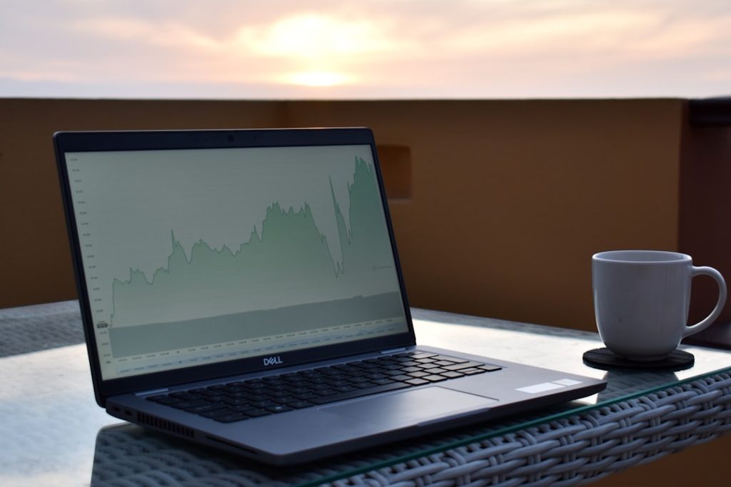 laptop displaying a financial chart with a coffee cup beside it
