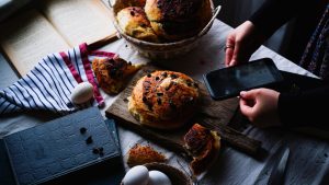 Artistic shot of homemade bread on a wooden board with a smartphone capture, embodying a rustic culinary scene. — Elements Ba