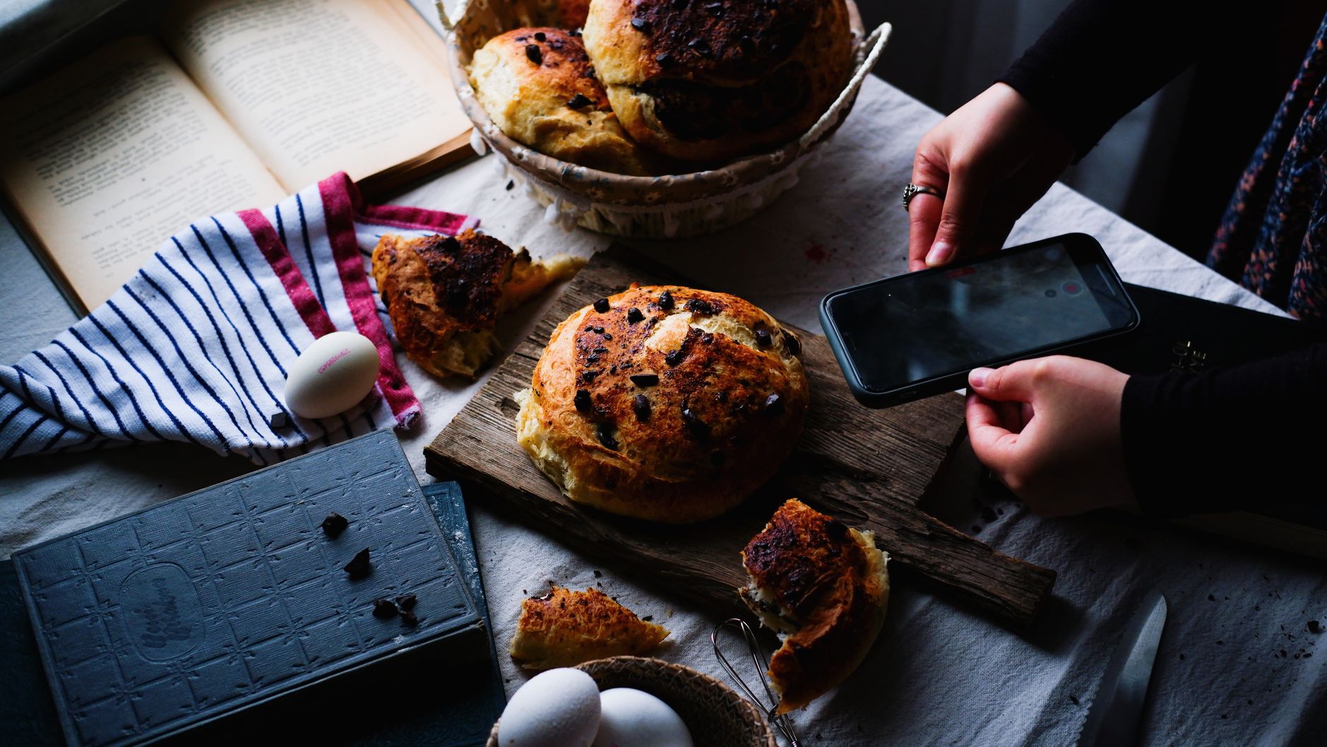 Artistic shot of homemade bread on a wooden board with a smartphone capture, embodying a rustic culinary scene. — Elements Ba